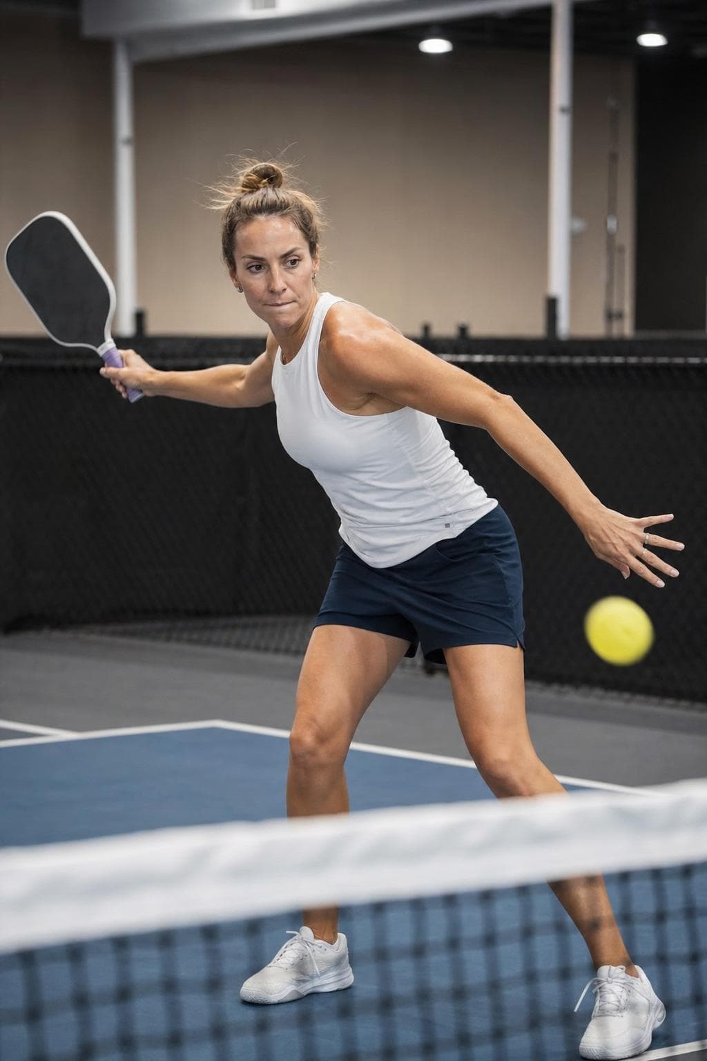 Players on an indoor pickleball court mid-rally